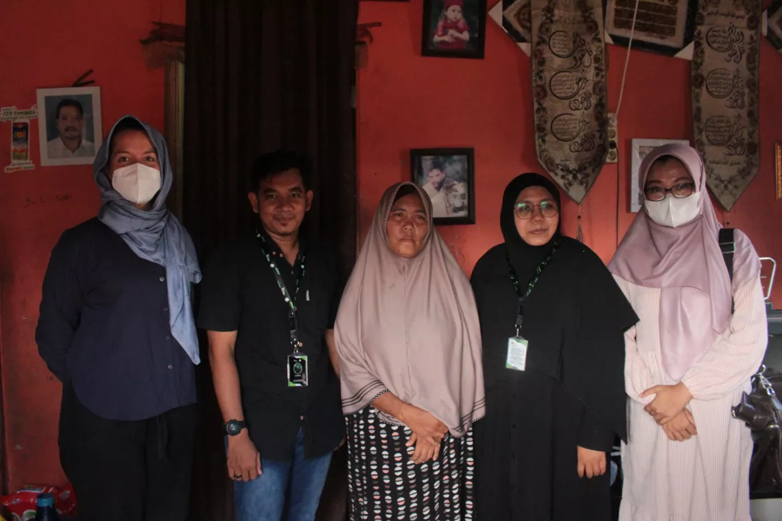 Ibu Ernawati (centre) stands in her home with Ronald and Ulfah (left and right of Ibu Ernawati) from BMA and Anna-Lisa and Hasnani from (far left and far right) from UNICEF Indonesia.